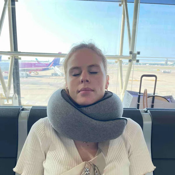 A woman resting at the departure gate in the WANDER+ Pillow